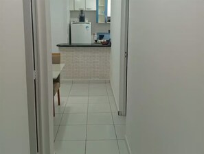 Ein schmaler Flur führt zu einer Küche mit Kühlschrank, Esstisch und Stühlen.