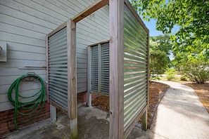 Uma casa com área externa coberta, uma mangueira e um caminho de concreto.