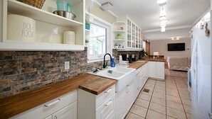 Een moderne keuken met witte kastjes, een houten aanrechtblad en een achterwand van steen.
