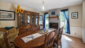 Een eetkamer met een houten tafel, stoelen, een kast en een hanglamp.