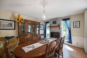 Uma sala de jantar com mesa de madeira, cadeiras, armário e luminária pendente.