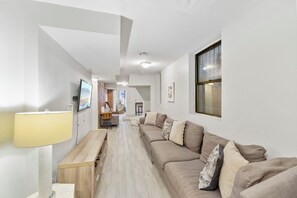 Ein modernes Wohnzimmer mit einer Couch, einem Fernseher und einer Lampe.