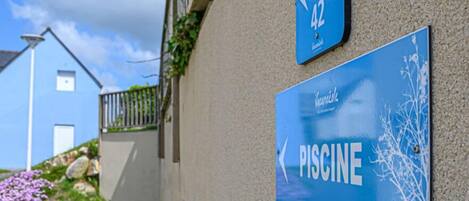 Un panneau bleu avec l’inscription « PISCINE » indiquant la présence d’une piscine.
