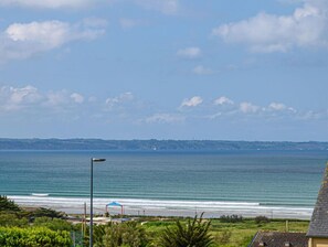 Blick auf die Küste mit Strand, blauem Himmel und einer fernen Uferlinie.
