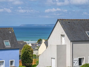Ein Küstenwohngebiet mit Häusern, freiem Blick auf das Meer und einer entfernten Küstenlinie.