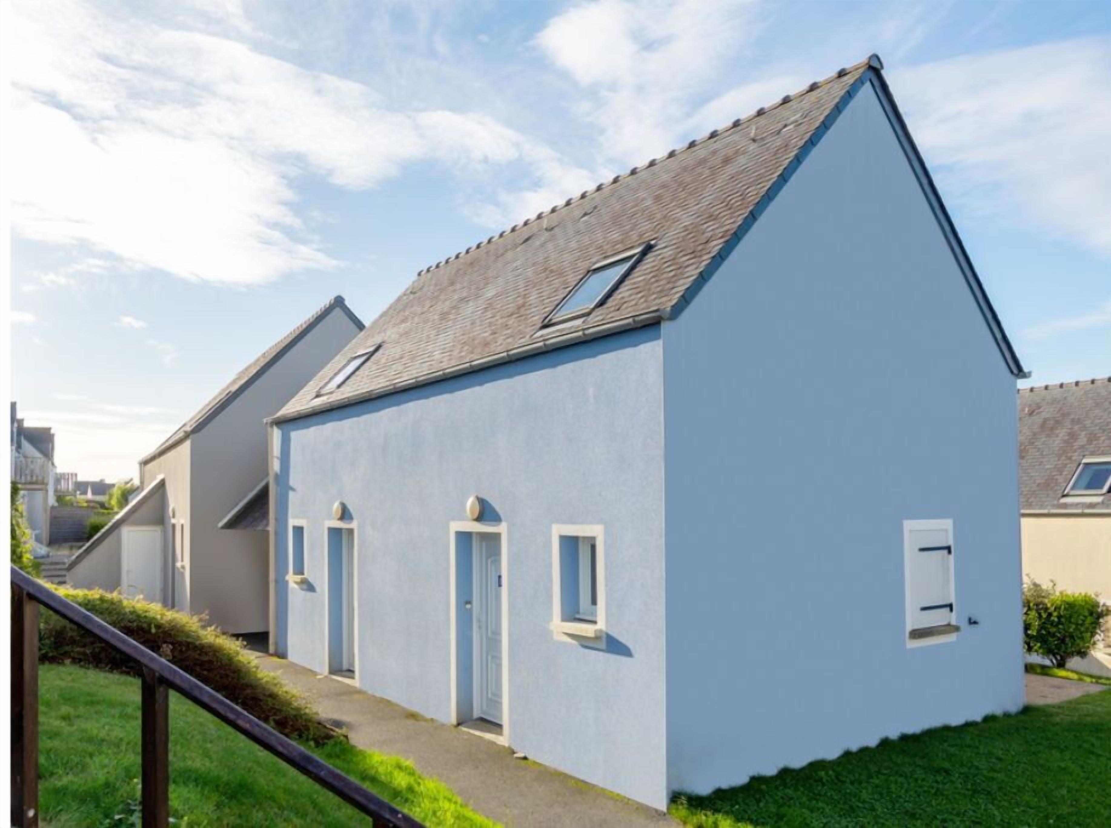 A modern two-story house with a sloped roof, a small porch, and a visible staircase leading to the entrance.