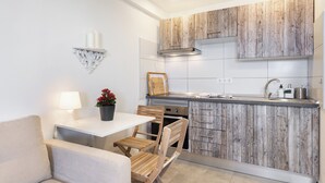 Eine kleine Küche mit Holzausstattung, einer weißen Arbeitsplatte, einem eingebauten Ofen und einem Essbereich mit Tisch und Stühlen.