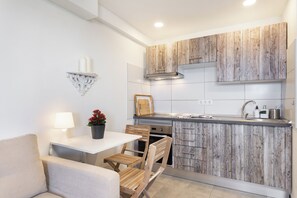 Eine kleine Küche mit Holzausstattung, einer weißen Arbeitsplatte, einem eingebauten Ofen und einem Essbereich mit Tisch und Stühlen.
