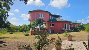 Una casa de dos pisos con fachada roja, un porche cubierto y un jardín bien cuidado.