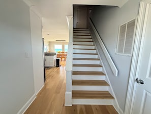 A staircase leading to a second-floor area with a kitchen and dining area visible in the background.