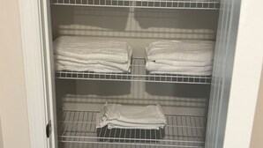 A closet with multiple shelves, some holding folded towels.