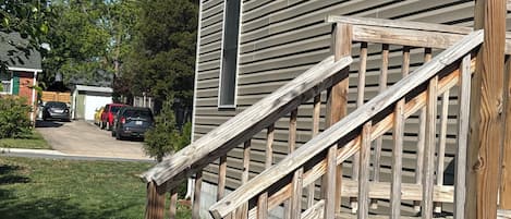 Una casa residencial con una escalera de madera que lleva a un porche.