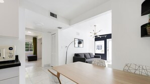 A modern kitchen with a built-in oven, a dining area with a wooden table and chairs, and a living space with a sofa and a TV. - Alton Apts by At Mine Hospitality (Miami Beach)