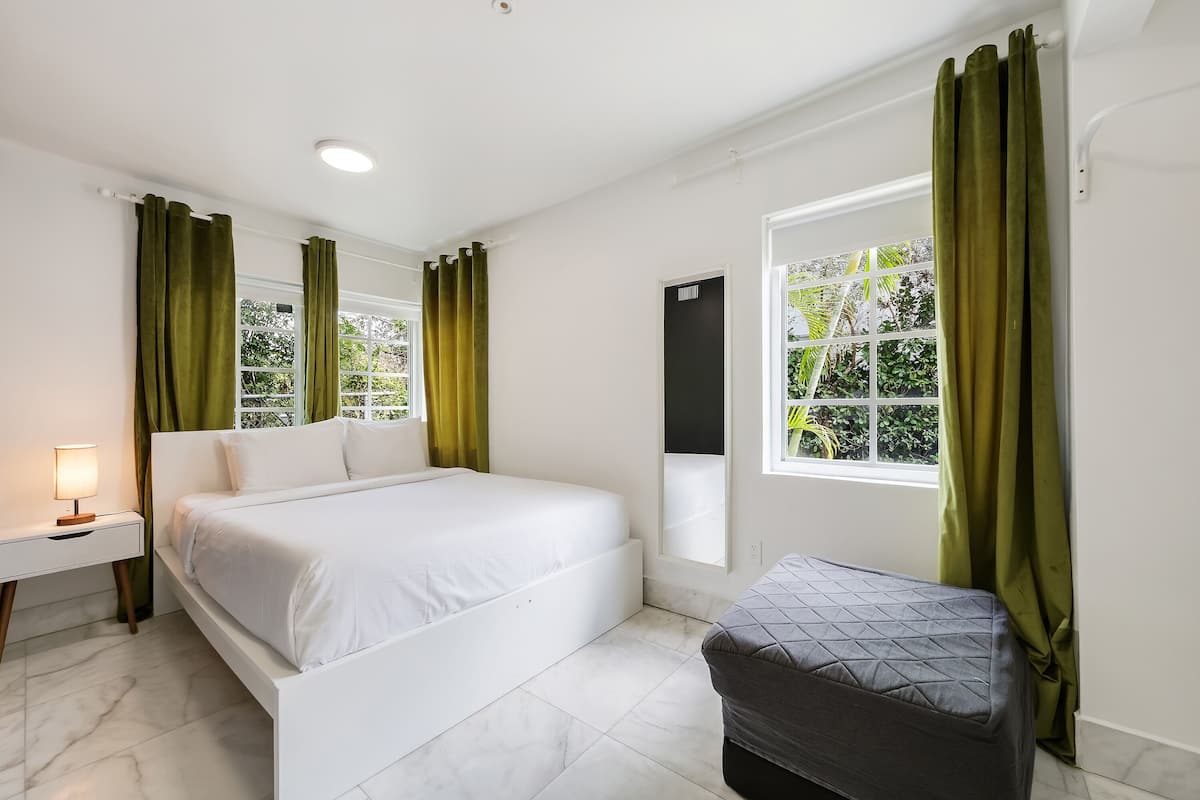 Ein Schlafzimmer mit Bett, Nachttisch und einem fenster mit Vorhängen.