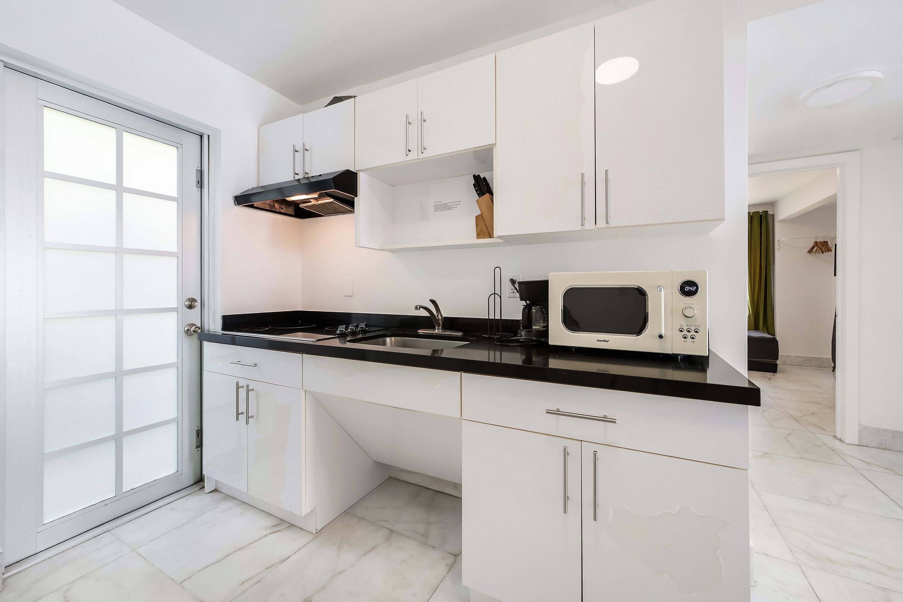 A modern kitchen with white cabinets, a black countertop, and a microwave.
