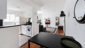 A modern kitchen with white cabinets, a black countertop, and a dining area with a black table. - Alton Apts by At Mine Hospitality (Miami Beach)
