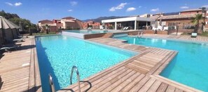A pool area with wooden decks, lounge chairs, and a covered seating area. - Apartment 78, Résidence Les hameaux de Saint-Cyprien, 5 minutes from the beach. (Lecci)