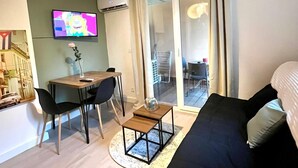 Ett modernt vardagsrum med en soffa, ett matbord, stolar, en tv och en balkong med utsikt.