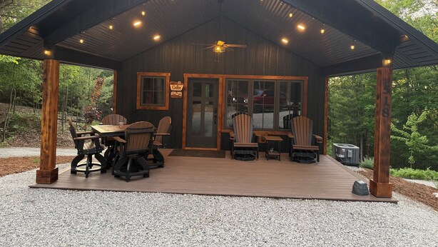 A cabin with a covered patio, wooden furniture, and a sign indicating it is a cabin.