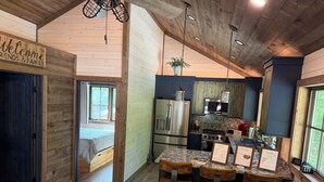 A rustic cabin interior with a wooden interior, a kitchen with modern appliances, and a dining area with bar stools.