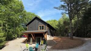 A rustic cabin with a porch, surrounded by trees.