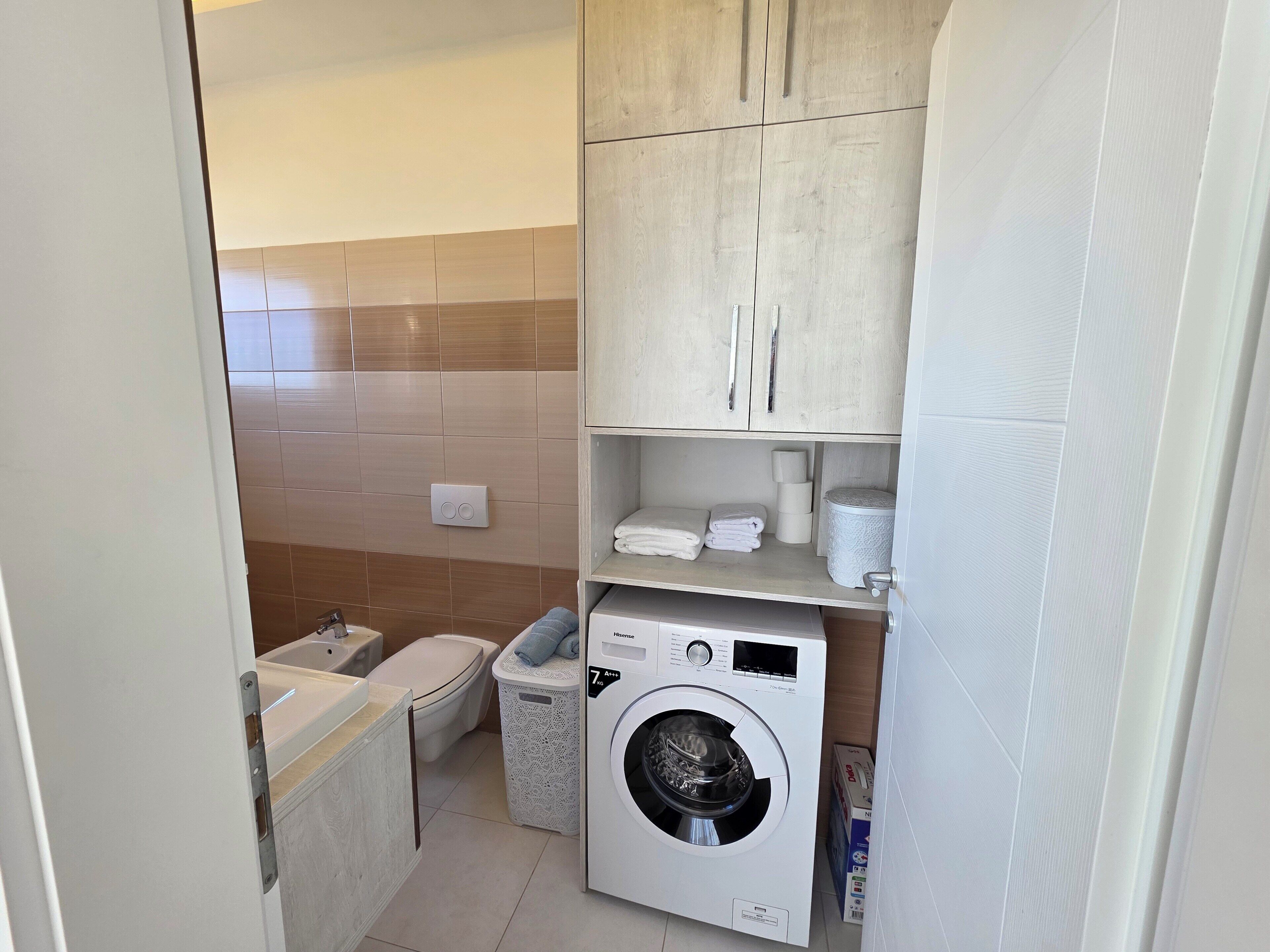 Un baño pequeño con inodoro, lavabo y lavadora.