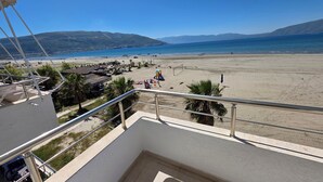 En balkon med udsigt over en strand, palmer og bjerge.