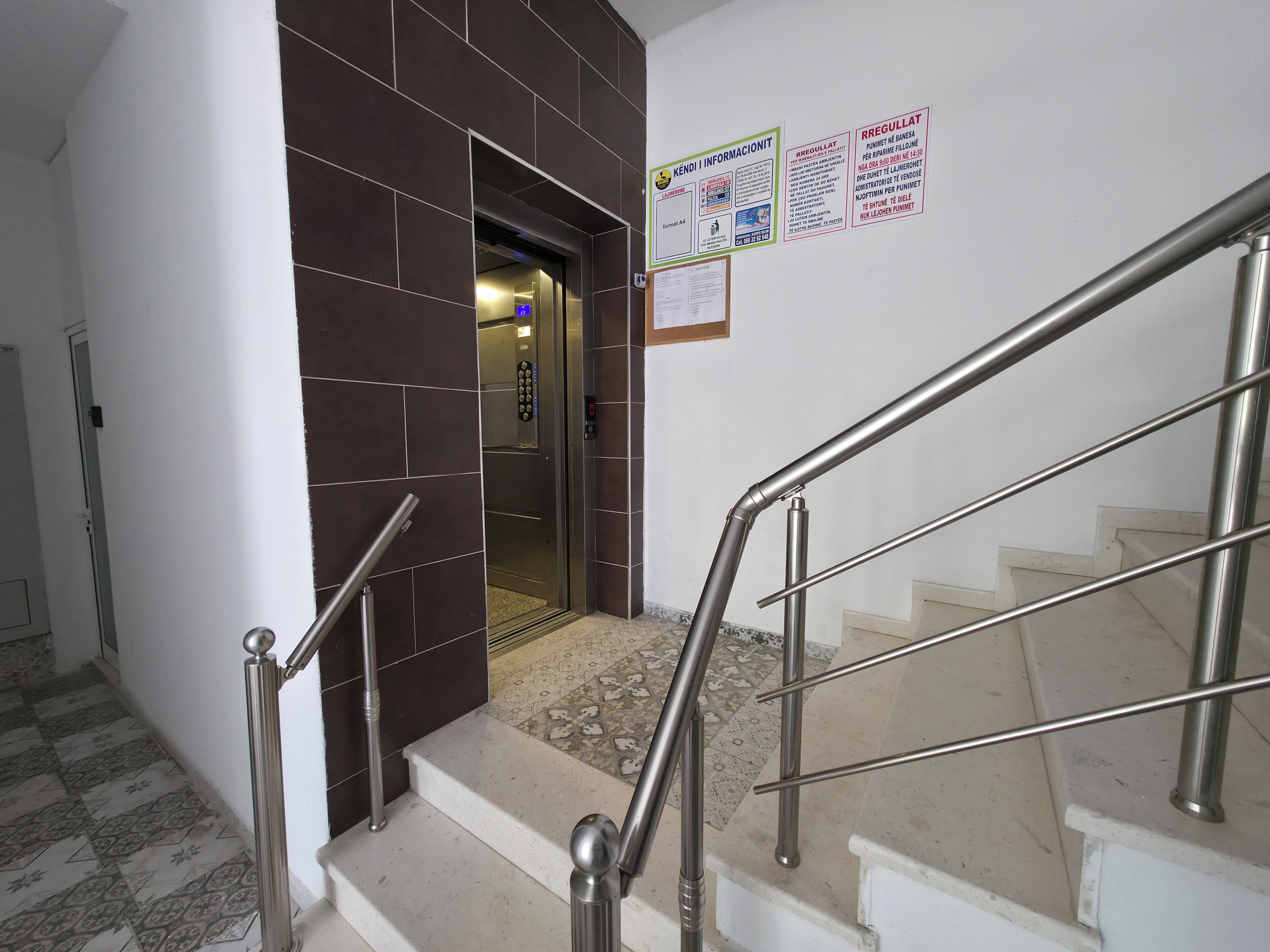Una escala amb baranes metàl·liques que condueix a un ascensor.