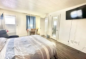 A hotel room with a bed, a desk, a chair, a TV, and a door. - Flora Motel (Flora)