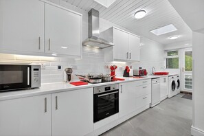 Een moderne keuken met witte kasten, een magnetron, oven en vaatwasser.