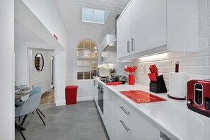 A modern kitchen with white cabinetry, a red toaster, and a red trash bin. - SuperHost Long Stays, Parking, Garden, Fast Wifi. (Lisburn and Castlereagh)