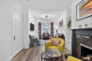A modern living room with a fireplace, a sofa, a coffee table, and a TV. - SuperHost Long Stays, Parking, Garden, Fast Wifi. (Lisburn and Castlereagh)