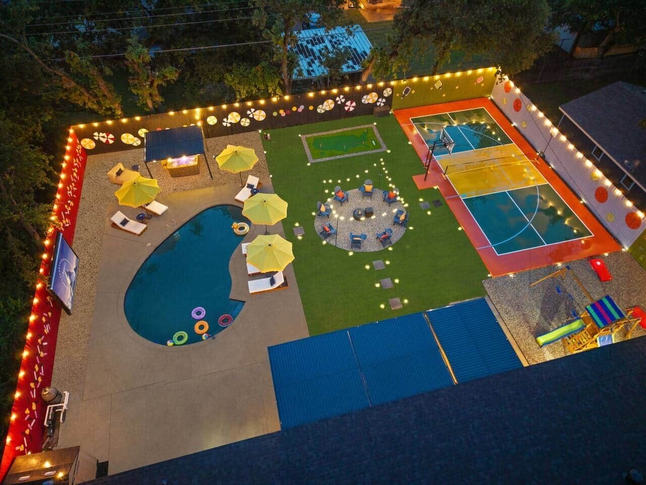 An outdoor area with a pool, a basketball court, and a circular seating area with umbrellas.