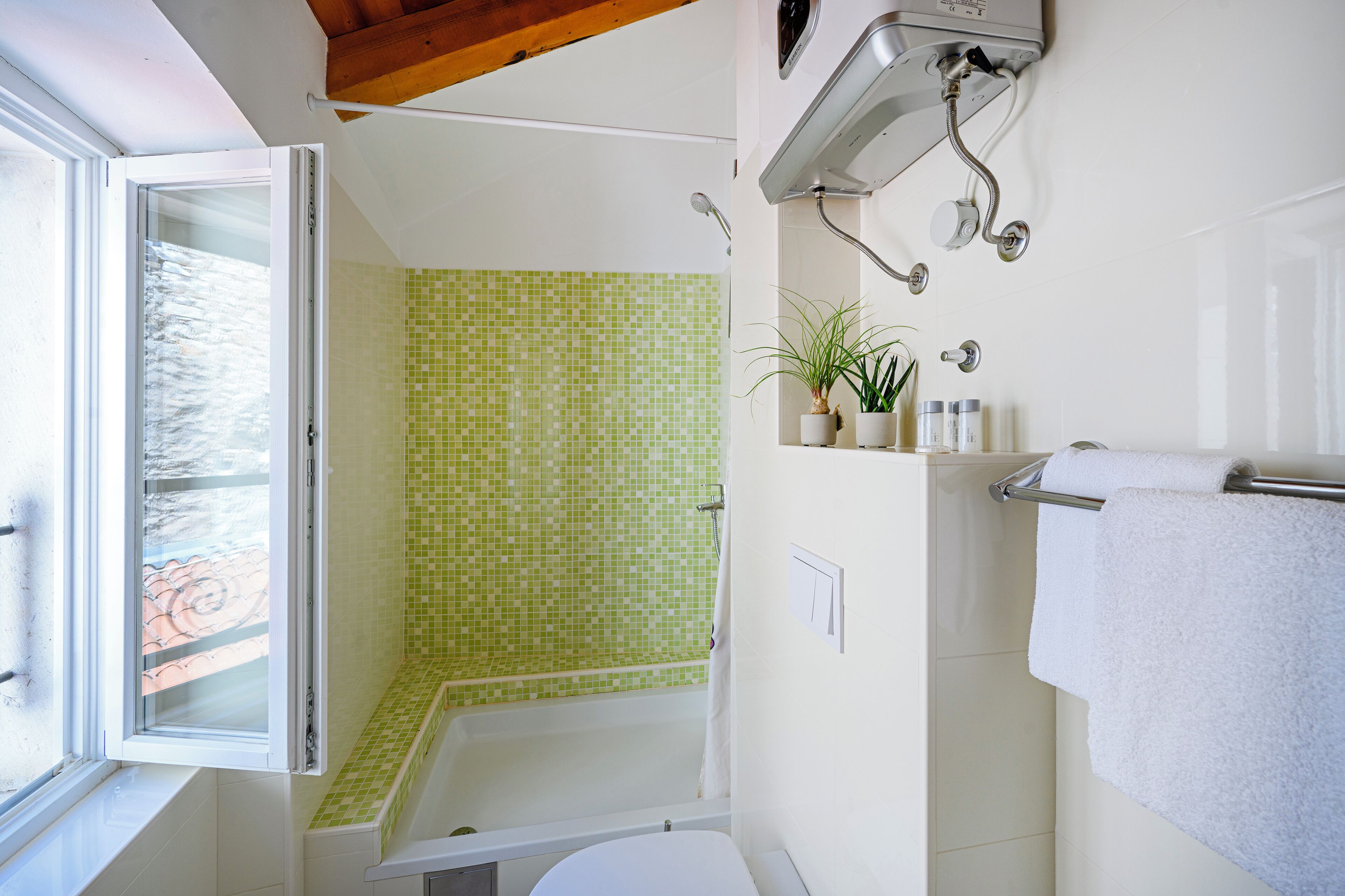 Ein Badezimmer mit Dusche, Toilette, Fenster und Handtuchhalter.