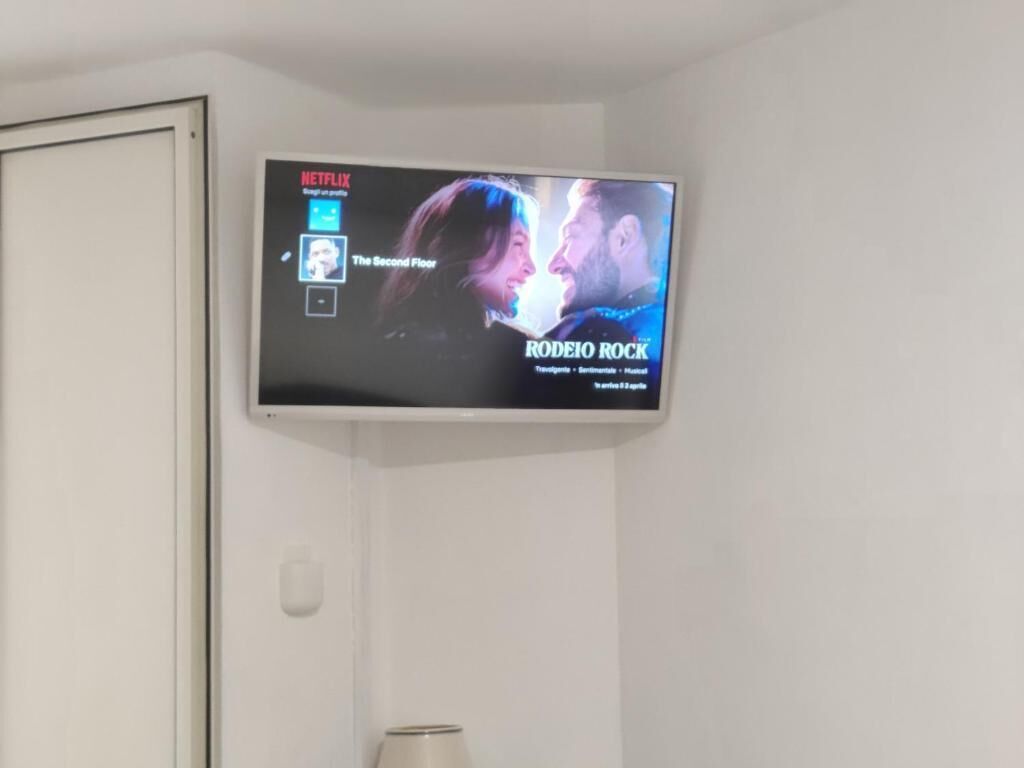 Un televisor montado en la pared mostrando una película titulada 'Rodeo Rock' con elementos de la interfaz de Netflix visibles.