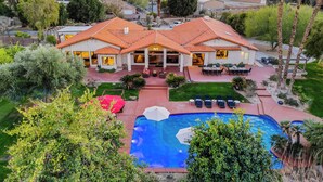 A large house with a swimming pool, surrounded by greenery and mountains in the background. - 20 Beds, 2 Pickleball Courts, Basketball, 4 Acres,
Gym and Gameroom (Bermuda Dunes)