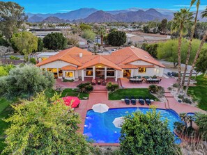 A large house with a swimming pool, surrounded by greenery and mountains in the background. - 20 Beds, 2 Pickleball Courts, Basketball, 4 Acres,
Gym and Gameroom (Bermuda Dunes)