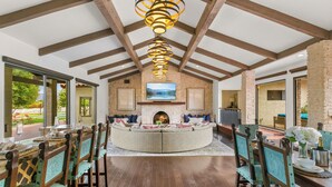 A spacious living area with a fireplace, a TV mounted on the wall, and a dining area with wooden furniture. - 20 Beds, 2 Pickleball Courts, Basketball, 4 Acres,
Gym and Gameroom (Bermuda Dunes)