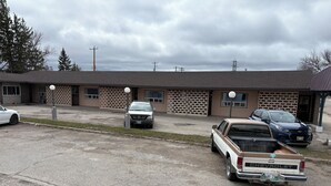 A motel with multiple rooms, a parking lot, and a building with a brick facade. - Casey's Inn (Lac du Bonnet)