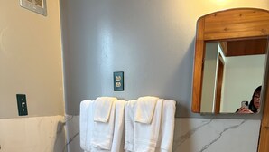 A bathroom with a toilet, sink, and two towels hanging on the wall. - Casey's Inn (Lac du Bonnet)