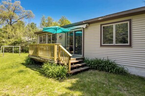 Een gelijkvloers huis met een houten terras, een overdekte veranda en een groot raam.