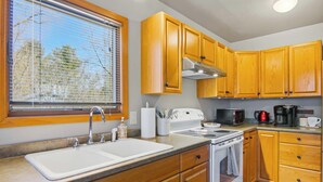 Una cocina con gabinetes de madera, un lavamanos, una estufa y un microondas.