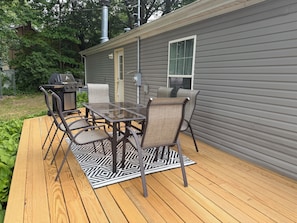 A deck with a table and chairs, a grill, and a window. - Delightful 4-bedroom house across from Warren Dunes! (Sawyer)