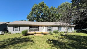 A single-story house with a front porch, a small garden, and a lawn.