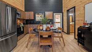 Una cucina moderna con mobili in legno, elettrodomestici in acciaio inossidabile e un'area pranzo con tavolo e sedie in legno.