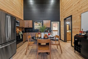 A modern kitchen with wooden cabinets, stainless steel appliances, and a dining area with a wooden table and chairs. - Indoor Pool, Mtn Views, Hot Tub, Couples Cabin, Fire Pit, & Close to Strip (Pigeon Forge)