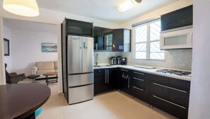 A modern kitchen with black cabinets, a stainless steel refrigerator, a microwave, and a gas stove. - 2Bedroom Apt. With Small Swimming Pool (San Juan)