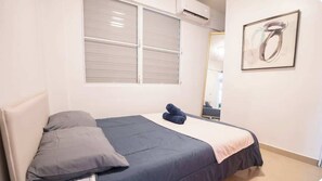 A bedroom with a bed, pillows, a window, and a wall-mounted air conditioner. - 2Bedroom Apt. With Small Swimming Pool (San Juan)