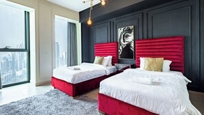 Quarto de hotel moderno com duas camas, uma janela ampla com vista para a cidade e decoração em tons de preto e vermelho.