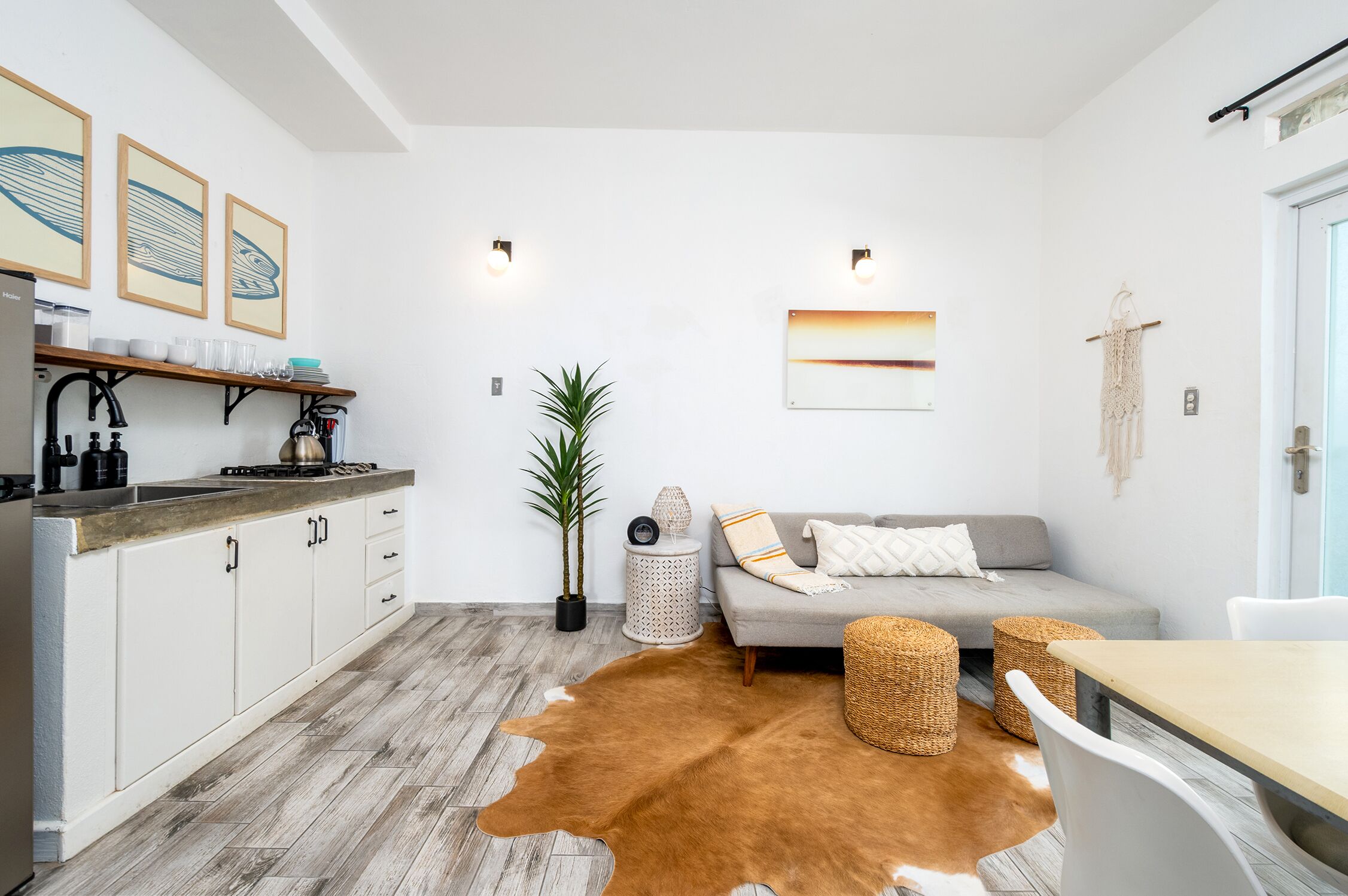 A modern kitchen with white cabinets, a wooden countertop, and a cowhide rug.